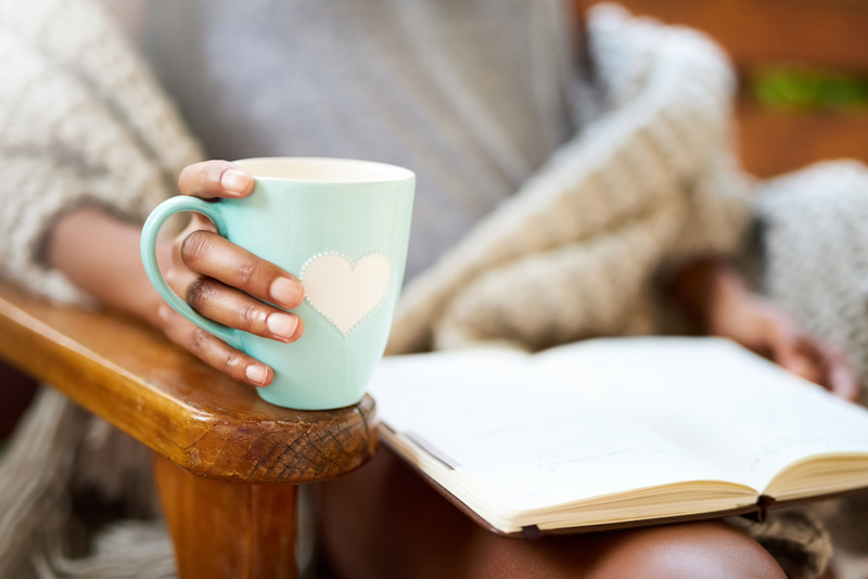 Frau, die eine Tasse hält und ein Buch liest