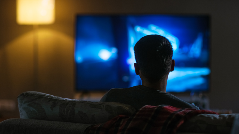 Junge, der im Dunkeln vor dem Fernseher steht