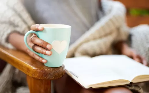 Woman holding mug and reading a book
