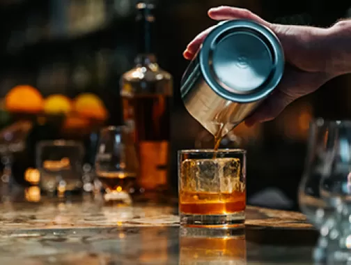 Bar tender pouring whiskey into a glass